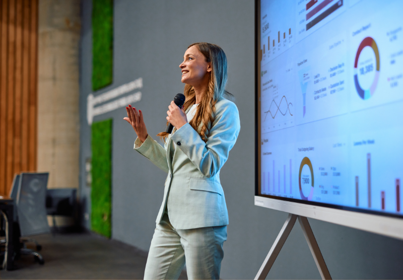 A woman speaking in front of a projector screen
